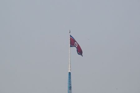 A North Korean flag flutters on top of a tower
