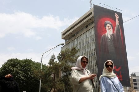 People walk near a billboard depicting Iran's late Supreme Leader