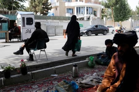 An Afghan woman walks among Taliban soldiers at a checkpoint