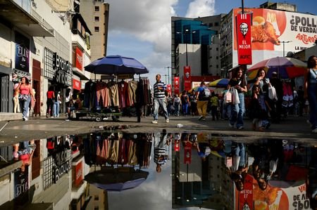 People walk as they are reflected in a puddle on