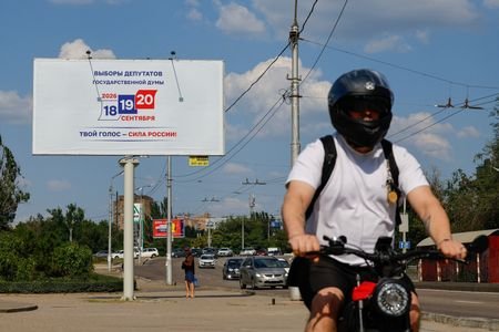 A cyclist passes a billboard announcing Russia's upcoming parliamentary election