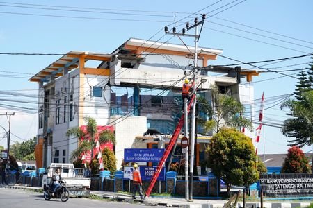 A utility worker engages in electrical cable repairs after an