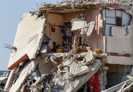 Palestinians sit inside a house damaged during the war in