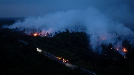 A drone view shows smoke rising from a wildfire burning