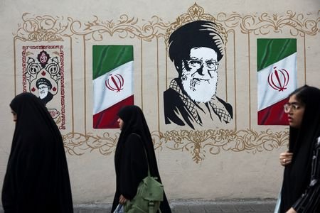 FILE PHOTO: People walk by a mural depicting Iran's late