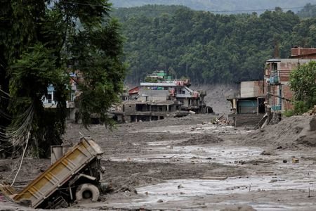Mud covers houses and a road following a flash flood