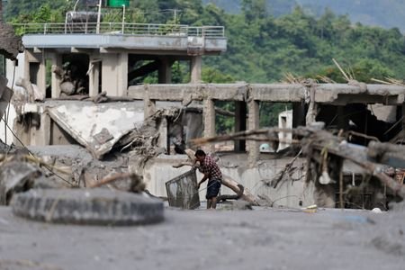 A man salvages his belongings from mud following devastating floods,