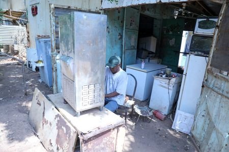 A refrigerator maintenance technician repairs a refrigerator in a neighborhood