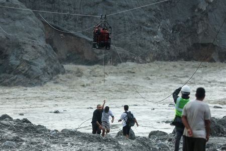 Men pull a makeshift zip line carrying people across the