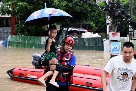 Rescue worker holds a child while evacuating residents amid flooding