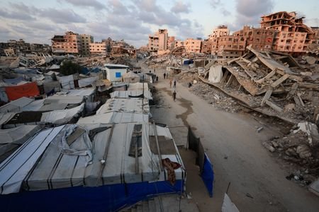 Palestinians walk past the rubble of residential buildings destroyed, in