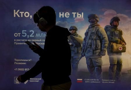 A man walks past a board promoting military service in