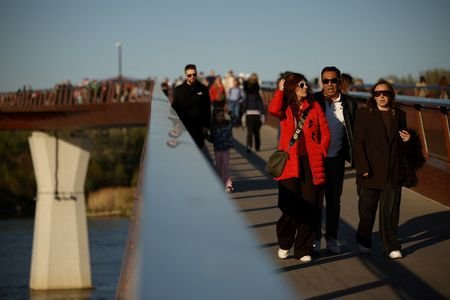 People walk across a pedestrian bridge over the Vistula