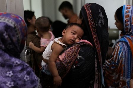 A woman carries a child, who suffers from measles, for