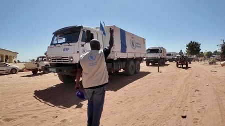 A staff member gestures at World Food Program (WFP) trucks