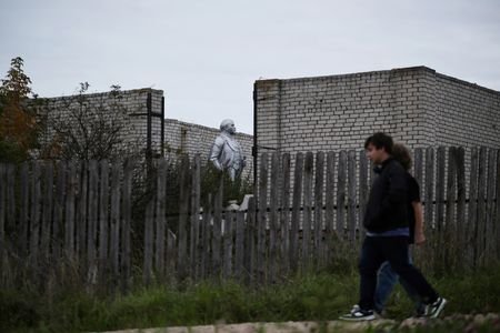 People walk past a statue of Vladimir Lenin standing inside