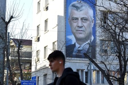 Man walks near a banner displaying former Kosovo President Hashim