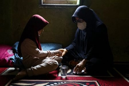 Mimi Marlina, 45, gives a medicine to her daughter inside