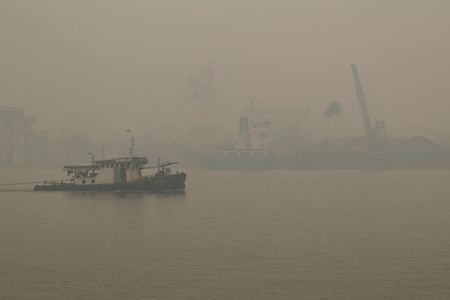 A tugboat sails along the Kapuas River amid thick haze