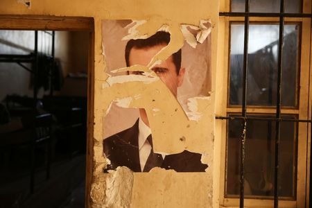 FILE PHOTO: A damaged portrait of former Syrian President Bashar