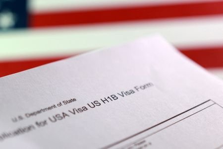 FILE PHOTO: A U.S. flag and a U.S. H-1B Visa