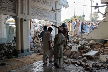 People gather at a damaged mosque following a suicide attack
