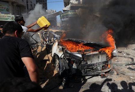 Palestinians attempt to extinguish a fire following an Israeli air