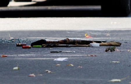 A shotgun and shotgun shells lie on the ground at