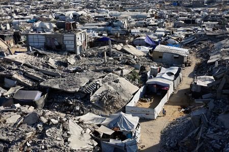 Palestinian children walk past the rubble of residential buildings destroyed