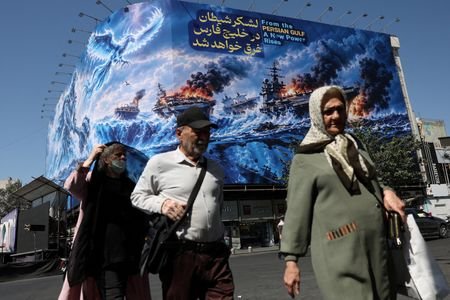 FILE PHOTO: People walk past a billboard about the Strait
