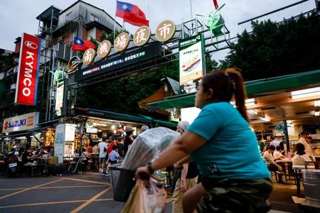 A person rides a bike past Taiwan flags above the