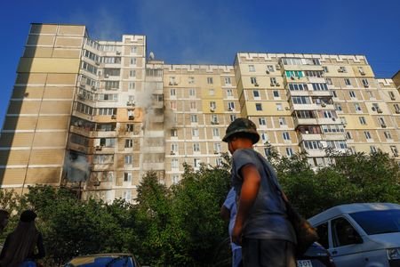 Residents gather at the site of a residential building hit