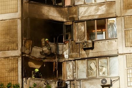 Firefighters work at the site of a residential building hit