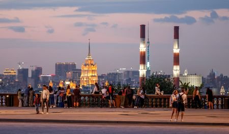 People walk at Vorobyovy Gory viewpoint after sunset with the