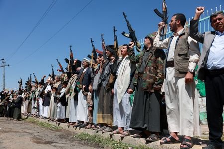 Houthi supporters carry weapons as they gather in solidarity with