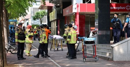 Firefighters and policemen gather outside the scene where several people