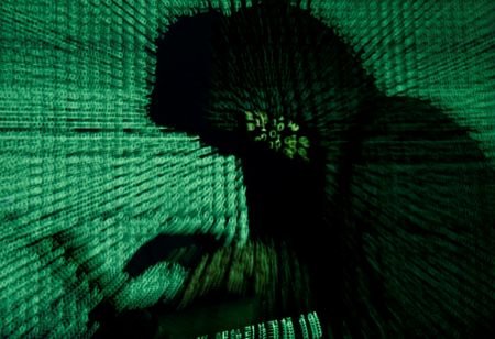 FILE PHOTO: Man holds laptop computer as cyber code is