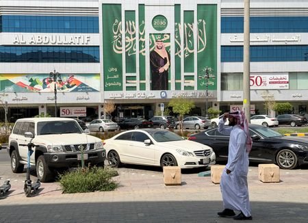 A Saudi man walks past a banner of Saudi Crown
