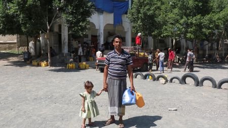 Displaced Yemeni, Ali Hassan, stands with his daughter, at a