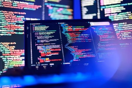 Computer code is displayed on multiple screens
