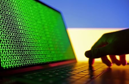 Illustration shows binary codes displayed on a laptop in front
