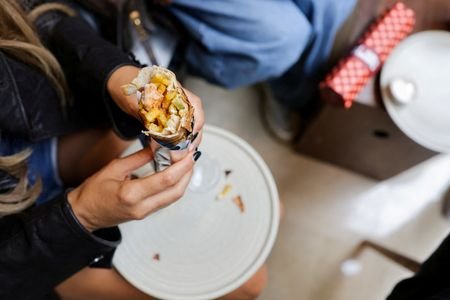 A person eats a chicken taouk sandwich at Glow Paradise