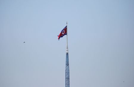 A North Korean flag flutters on top of a tower